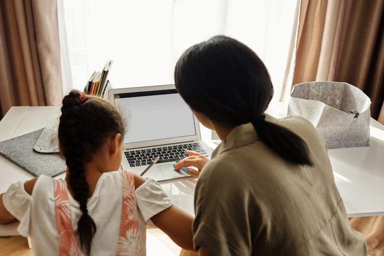Parent and child looking at a laptop while creating a pet remembrance site in the UK.